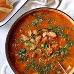 Farmhouse Cabbage Soup with Cannellini Beans and Kielbasa in white Dutch oven garnished with parsley.