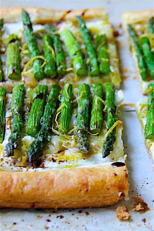 Asparagus, Spring Onion and Fontina Tart cut into quarters garnished with lemon zest.