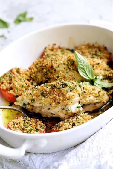 Pesto and Goat Cheese-Stuffed Chicken with Roma Tomatoes - Finished dish being served with serving fork from white baking dish