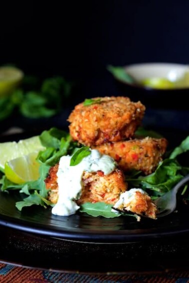 Stack of three Thai Salmon Cakes with Basil - Lime Mayonnaise on black plate.