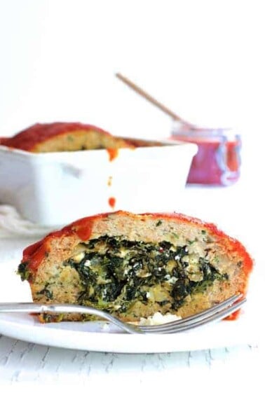 Slice of Spinach Feta Stuffed Turkey Meat Loaf on white plate showing the filling.