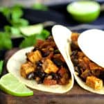 Two Tofu and Black Bean Tacos on wood cutting board.