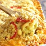 Spoonful of Hatch Green Chile Mac and Cheese being lifted from white baking dish.
