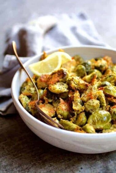 Lemon Parmesan Crusted Brussels Sprouts in white bowl with serving fork.