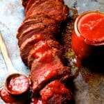Spice Rubbed Pork Tenderloin with Peach Chipotle Barbecue Sauce on baking sheet with the sauce in a jar and spooned over the pork tenderloin.