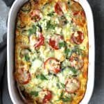 Four Cheese Strata with Zucchini and Tomatoes in white baking dish garnished with fresh parsley.