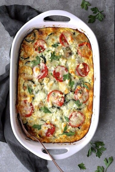 Four Cheese Strata with Zucchini and Tomatoes in white rectangular baking dish.