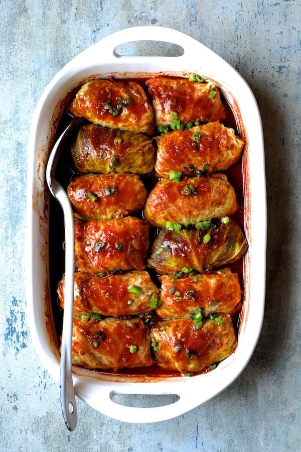 Photo of Spicy Asian Pork Cabbage Rolls on blue board with white metal spoon.