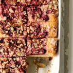 Easy Raspberry Coffee Cake in white rectangular baking pan, cut into pieces with silver server.