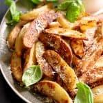 Oven Fries with Spicy Pesto Aioli on gray-rimmed platter garnished with fresh basil leaves.