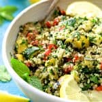 Quinoa Tabbouleh with Grilled Vegetables in white serving bowl garnished with fresh lemons.