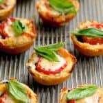 Mini Southern Tomato Pies on cooling rack garnished with fresh basil.