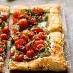 Two pieces of Cherry Tomato Tart on wood cutting board.