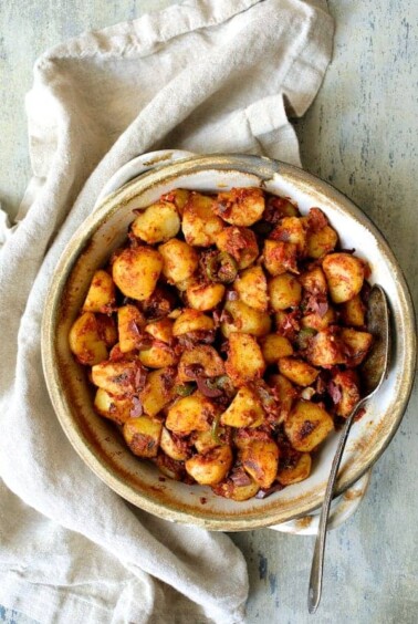 Chile Potatoes (Patatas Bravas Chilenas) in earthenware bowl with serving spoon.