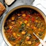 Spicy Kale, Butternut Squash and Lentil Soup with Bacon in a white enamel cast iron Dutch oven with soup ladle.