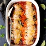 Stuffed peppers in white baking dish garnished with limes and cilantro sprigs after being baked.