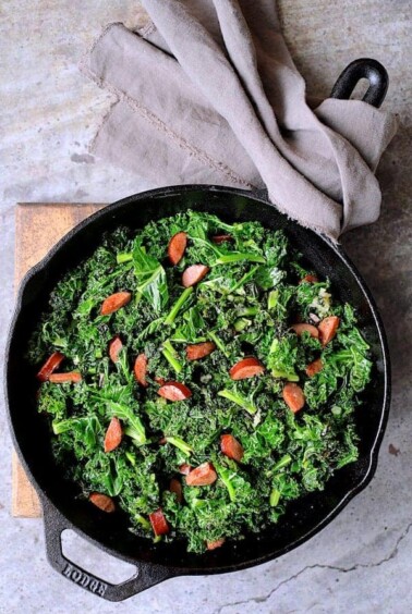 Spicy Sautéed Kale with Andouille Sausage in cast iron skillet.