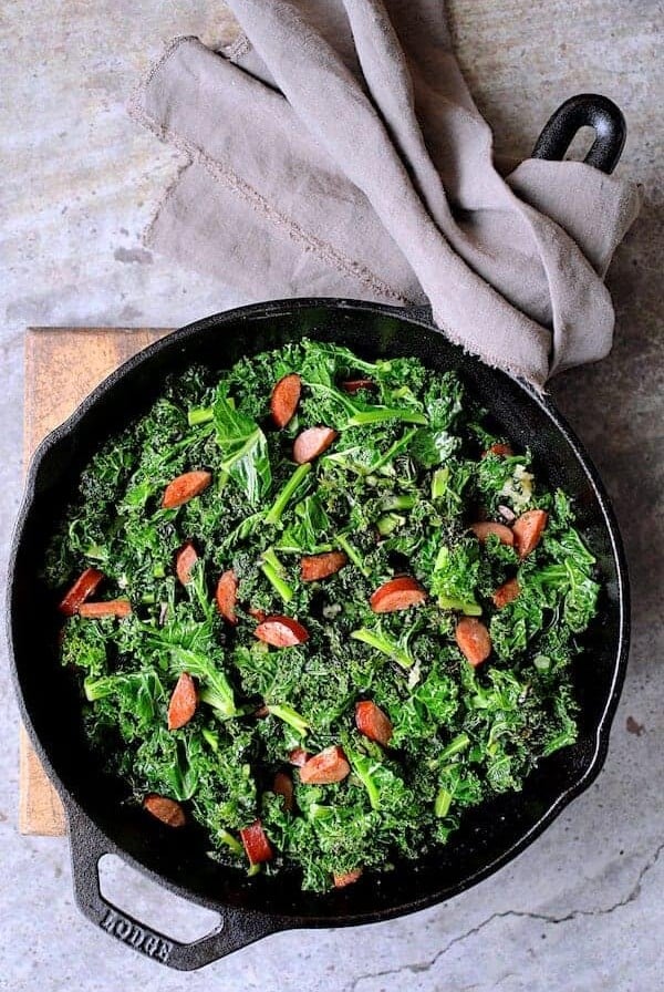 Spicy Sautéed Kale with Andouille Sausage in cast iron skillet.