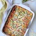 Breakfast Strata with Asparagus, Artichokes, Ham and Gruyere on cooling rack with serving fork.