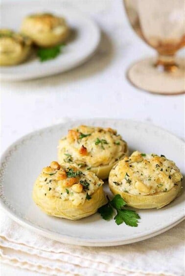 Three Lemon Parmesan Stuffed Artichoke Bottoms on white plate.