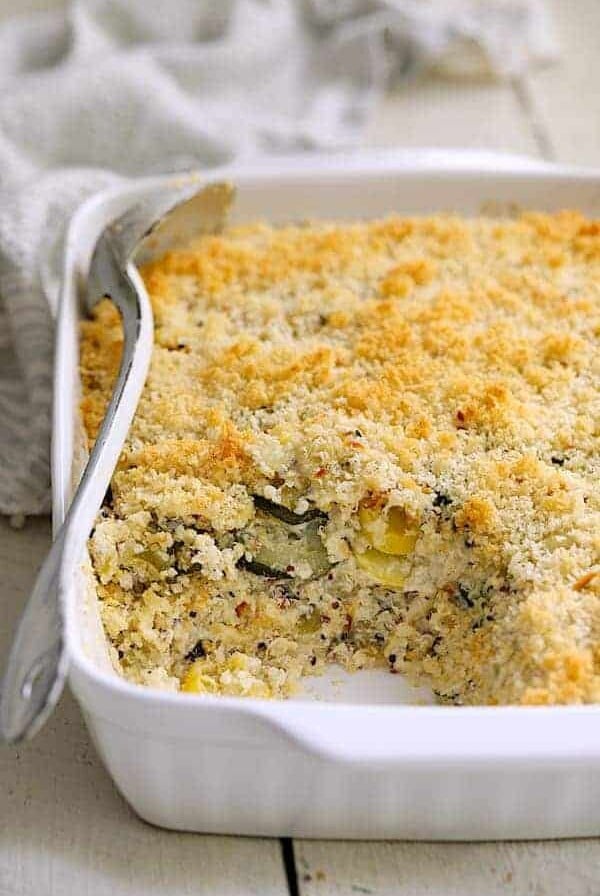 Zucchini, Yellow Squash and Quinoa Casserole in white baking dish with a serving removed.