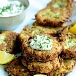 Zucchini Ricotta Fritters - Close-up shot of fritters with yogurt chive topping garnished with lemon slices