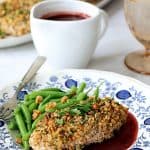 Walnut-Crusted Chicken with Pomegranate Sauce on blue and white plate with green beans.