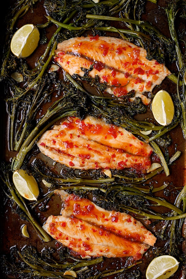 Photo of Sheet Pan Thai Sweet Chili Lime Baked Fish with Garlic Broccolini on sheet pan with lime wedges.