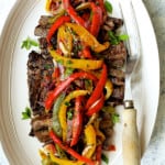 Grilled Marinated Skirt Steak with Peperonata - Overhead hero shot of dish on white oval platter with meat fork