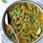 Vegan Thai Green Sweet Potato Curry - Overhead hero shot of curry in white cooking vessel garnished with cilantro and lime wedges on pale blue background