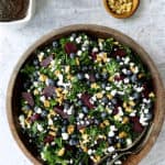 Massaged Kale, Beet and Blueberry Salad with Honey - Balsamic Dressing - Overhead hero shot of salad in wood bowl on gray stone background