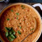 Photo of Thai Red Curry Sweet Potato and Lentil Soup in white Dutch oven with soup ladle.