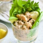 Photo of Sriracha Shrimp Remoulade Cocktail with lettuce, celery leaves, avocado wedge and lemon wedge.