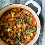 Classic French Ratatouille in white Dutch oven garnished with fresh basil.