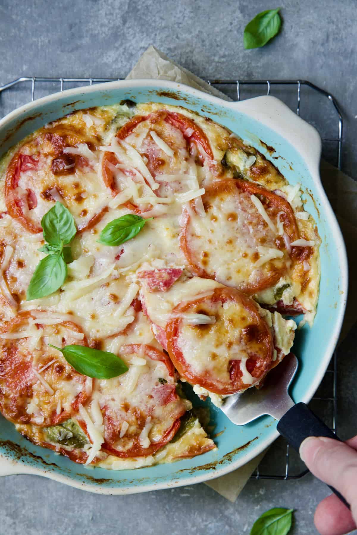 Crustless Southern Tomato Pie in pie pan with piece on pie server about to be served.