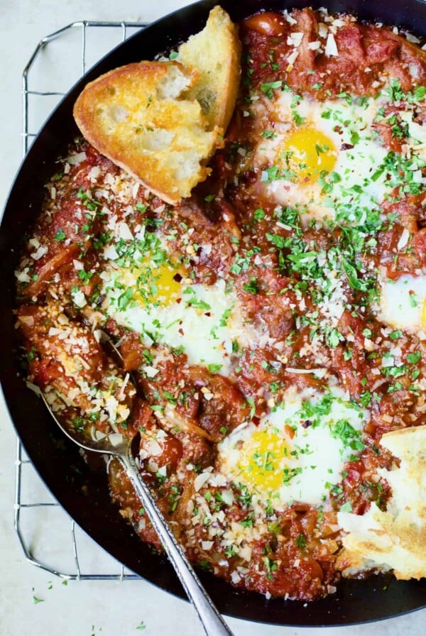 Eggs in Purgatory with Italian Sausage in skillet with toasted bread.