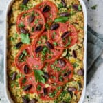 Greek Brown Rice and Vegetable Casserole in white baking dish garnished with fresh parsley.