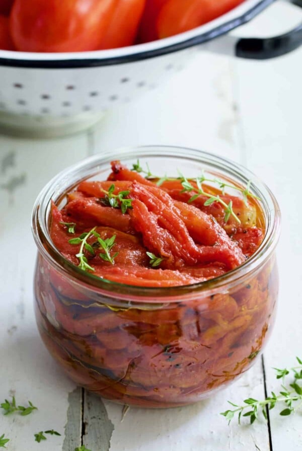 Tomato Confit in glass jar garnished with fresh thyme sprigs.