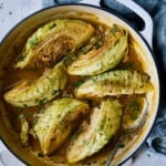 Cider Vinegar Braised Cabbage Wedges in white enamel cast iron skillet with blue napkin.