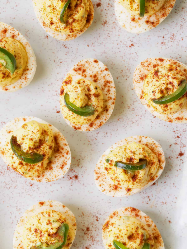 Nine Pimento Cheese Deviled Eggs with Jalapeno on white platter.