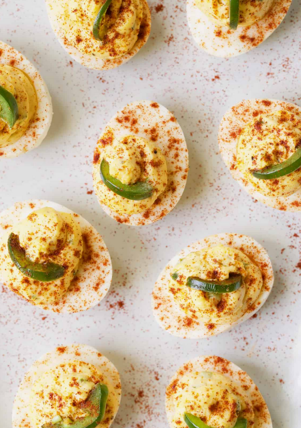 Nine Pimento Cheese Deviled Eggs with Jalapeno on white platter.