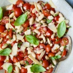 Tuscan Cherry Tomato and White Bean Salad in serving bowl with serving spoon.