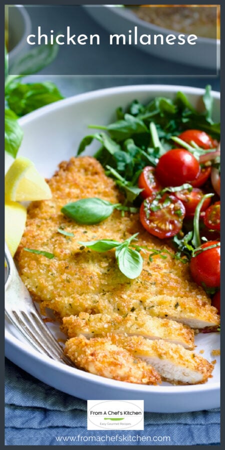 Chicken Milanese in white serving bowl with cherry tomato salad garnished with fresh basil leaves.