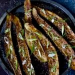 Six Miso-Glazed Eggplant halves on metal tray garnished with sesame seeds and scallions.