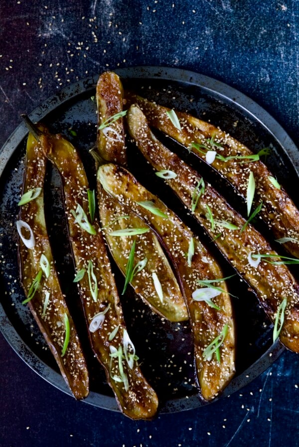 Six Miso-Glazed Eggplant halves on metal tray garnished with sesame seeds and scallions.