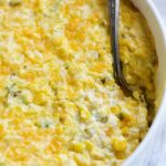 Cream Cheese Corn Casserole with Green Chiles in white oval baking dish with serving spoon.