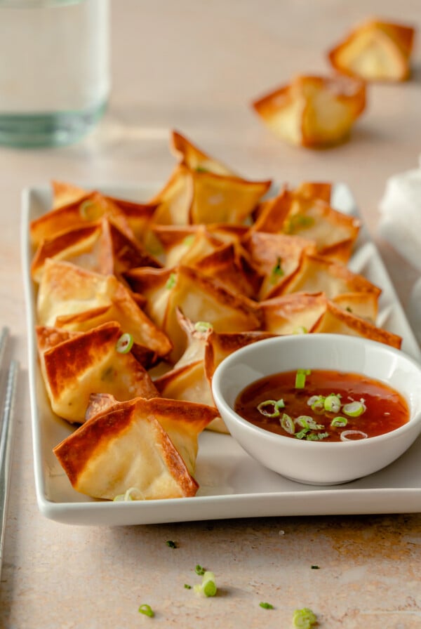 Air Fryer Crab Rangoon on white rectangular platter with dipping sauce.