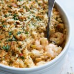 Shrimp and Crab Seafood Casserole in white baking dish with serving spoon scooping up shrimp and crab.