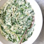Steakhouse Creamed Spinach in white oval bowl with serving spoon.