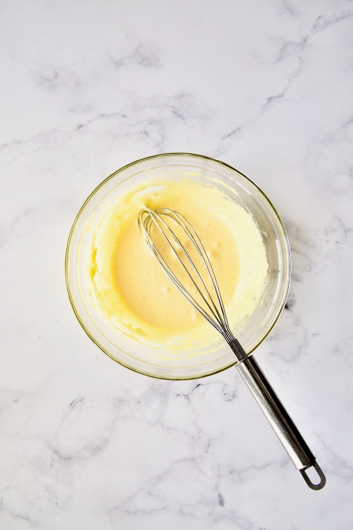 Whisk whisking together sugar and egg yolks until they're pale yellow in glass bowl.